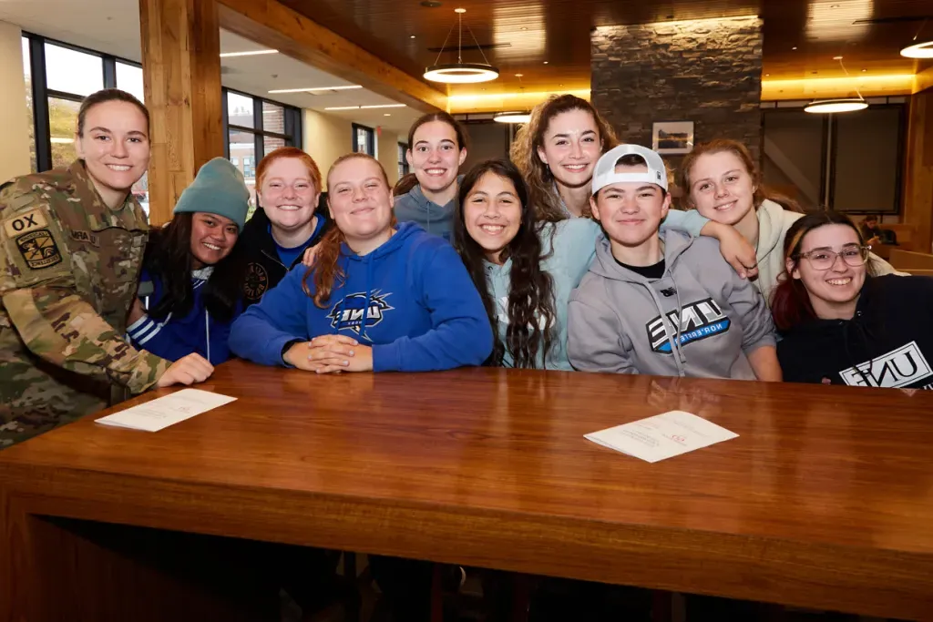 A group of U N E students smile with a veteran